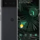 Front and back view of a foldable Google Pixel phone with a leafy wallpaper and weather widget on the screen, gray finish with Google 'G' logo on the back.